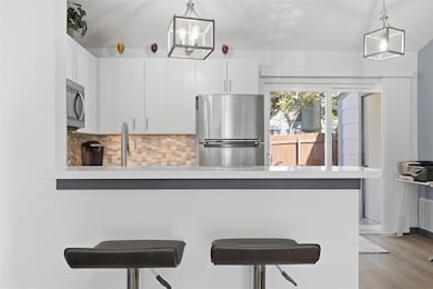Kitchen featuring stainless steel appliances, tasteful backsplash, a breakfast bar area, white cabinetry.