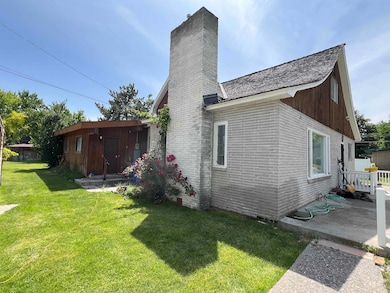 Rear view of house with a chimney, a yard, brick siding, and a patio