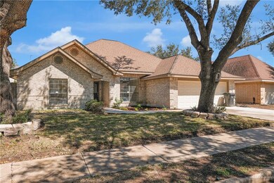View of front facade with an attached garage, brick siding, concrete driveway, roof with shingles, and a front yard