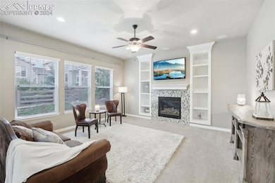 Living room featuring ceiling fan, a fireplace, pl