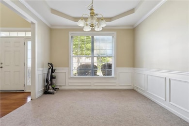 Foyer entrance with a raised ceiling, carpet, a ch