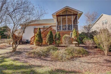 Rear view with screen porch, enclosed potting shed beneath, privacy wall to the left, & oversized deck.