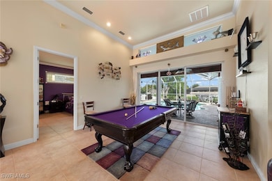 Game room with ornamental molding, a towering ceiling, billiards, and light tile patterned flooring