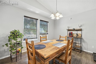 Dining space featuring a chandelier, wood finished floors, and lofted ceiling