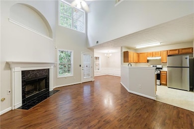 Unfurnished living room featuring a fireplace, wood finished floors, a chandelier, and a high ceiling