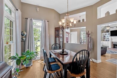 Dining space featuring wood finished floors, a chandelier, a fireplace, and a ceiling fan