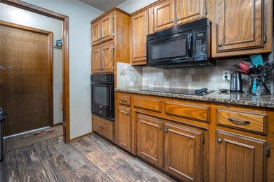 Kitchen featuring stone counters, backsplash, dark