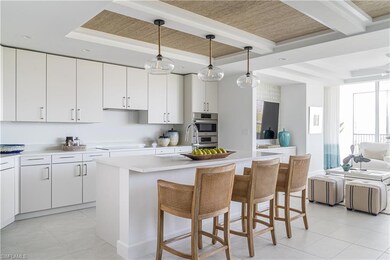Kitchen featuring a kitchen bar, a kitchen island with sink, light tile patterned floors, open floor plan, and white cabinetry weathered wood inlays and beams in the kitchen