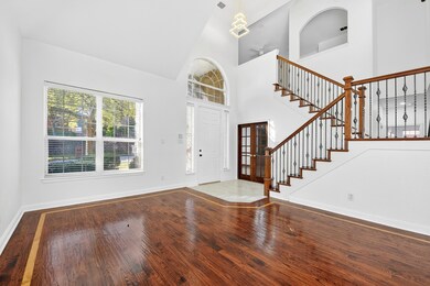 Foyer featuring french doors, wood-type flooring, stairs, and high vaulted ceiling