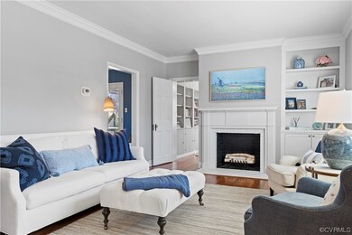 Living room featuring a brick fireplace, ornamental molding, and wood-type flooring