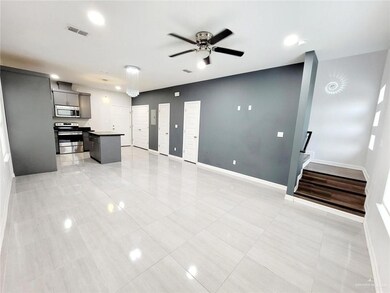 Unfurnished living room with visible vents, baseboards, ceiling fan, light tile patterned flooring, and stairs