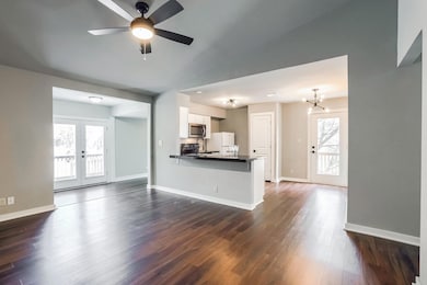 Unfurnished living room featuring a chandelier, dark wood finished floors, ceiling fan, and french doors