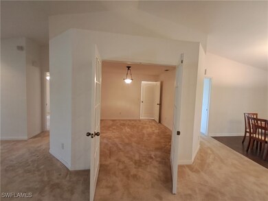 Hallway with carpet flooring and lofted ceiling