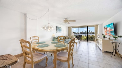 Dining space featuring floor to ceiling windows, a textured ceiling, a ceiling fan, light tile patterned flooring, and a chandelier