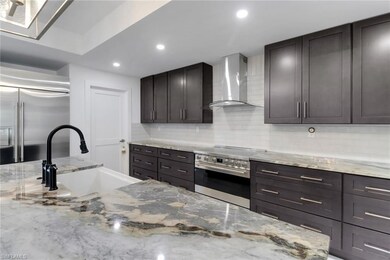 Kitchen with wall chimney range hood, high end appliances, a sink, backsplash, and recessed lighting