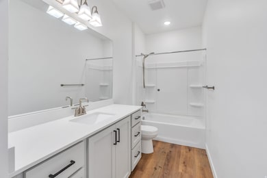 Bathroom featuring vanity, light wood-style floors, and shower / tub combination