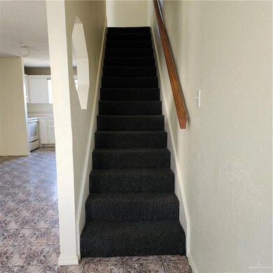 Staircase featuring a textured ceiling and a textured wall