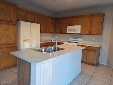 Kitchen featuring light tile patterned flooring, white appliances, brown cabinets, and light countertops