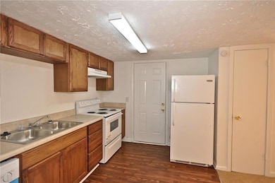 Kitchen with white appliances, sink, a textured ce