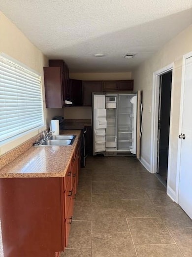 Kitchen featuring range, refrigerator, a textured ceiling, and light tile patterned flooring