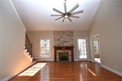 A view of the gas log fireplace and large two story vaulted ceiling with fan and light.