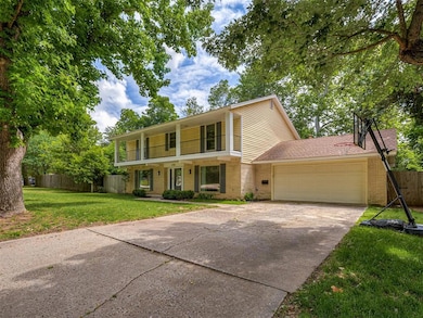 View of front of property featuring brick siding, a balcony, a garage, and concrete driveway