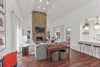 Living area featuring crown molding, dark wood-style flooring, a fireplace, high vaulted ceiling, and recessed lighting