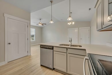 Kitchen with black electric range oven, a peninsula, hanging light fixtures, stainless steel dishwasher, and vaulted ceiling