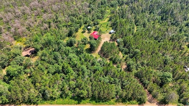 Aerial view of property and surrounding area with a heavily wooded area