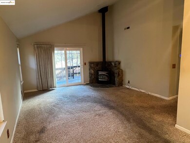 Unfurnished living room with a wood stove, high vaulted ceiling, and carpet floors
