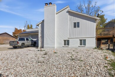 View of property exterior featuring a chimney, driveway, brick siding, and a deck