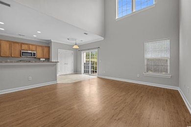 Unfurnished living room with light wood-style floors, a high ceiling, crown molding, and recessed lighting