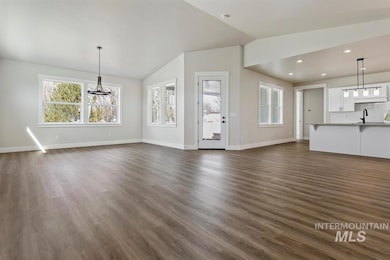 Unfurnished living room featuring vaulted ceiling, a chandelier, dark wood-style floors, and recessed lighting