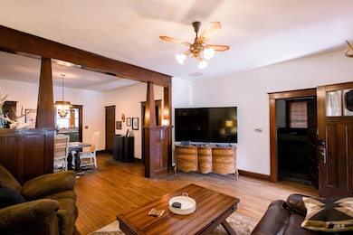 Living area featuring ceiling fan, wood finished floors, beam ceiling, and a chandelier