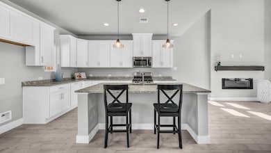 Kitchen with white cabinetry, light stone counters