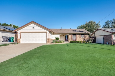 Ranch-style house featuring a front lawn, concrete driveway, brick siding, and a garage