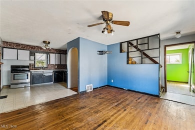 Kitchen featuring healthy amount of natural light, stainless steel electric range oven, arched walkways, a textured ceiling, and a ceiling fan
