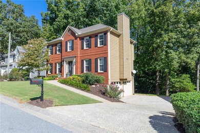 Featuring side-entry garage, and a long driveway tucked next to a wooded backdrop.