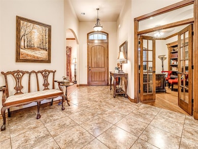 Foyer featuring baseboards, arched walkways, and tile patterned flooring