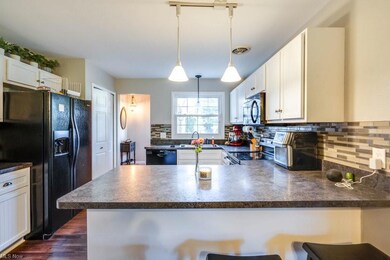Kitchen featuring backsplash, white cabinets, blac