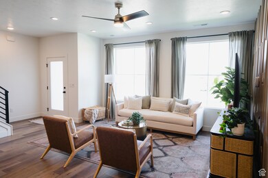 Living room with wood finished floors, a ceiling fan, and recessed lighting