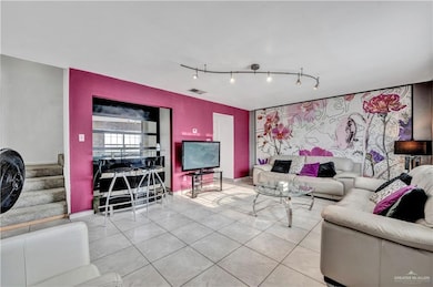 Living area featuring track lighting, tile patterned flooring, stairway, and baseboards