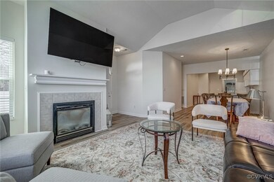 Living room with baseboards, vaulted ceiling, a fi