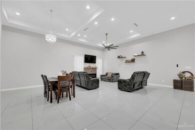 Living room featuring ceiling fan with notable chandelier and a raised ceiling