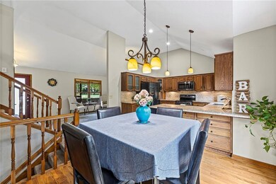 Dining area with high vaulted ceiling, a chandelier, stairs, and light wood finished floors