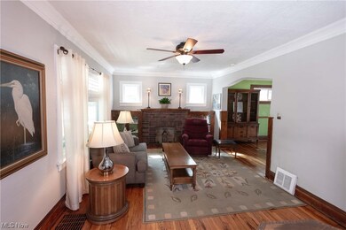 Hardwood floored living room features stained woodwork, ceiling fan and crown molding. Plenty of natural light.
