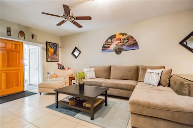 Living area with ceiling fan and light tile patte