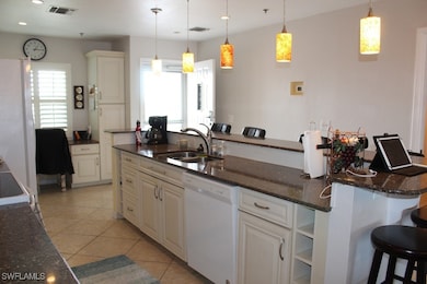 Kitchen with a kitchen bar, visible vents, light tile patterned flooring, dishwasher, and a sink