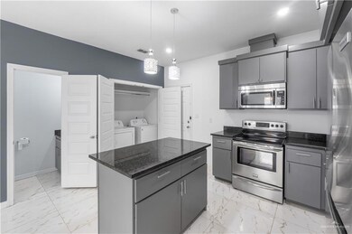 Kitchen with gray cabinets, marble finish floor, appliances with stainless steel finishes, and washer and dryer