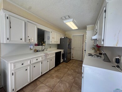 Kitchen with white cabinets, tile patterned flooring, light countertops, and a textured ceiling